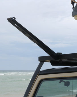 Mount the base plate to the slats on the sides of a Front Runner Roof Rack Tray, then quickly snap in and retract the folded arm for the perfect solution for hanging your solar shower or showerhead.